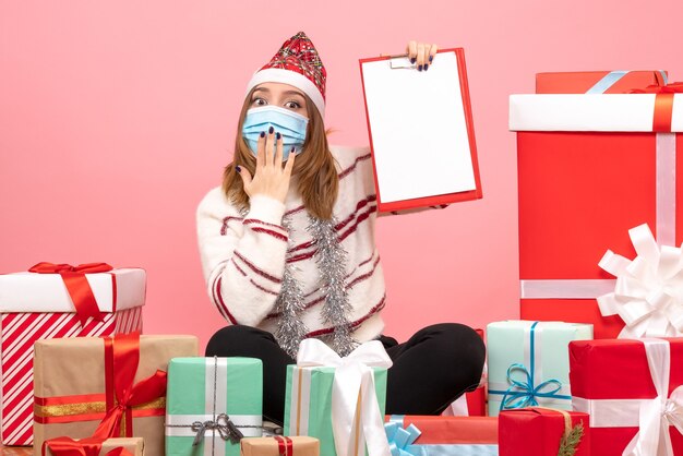 Vue de face jeune femme assise autour de cadeaux avec note de fichier