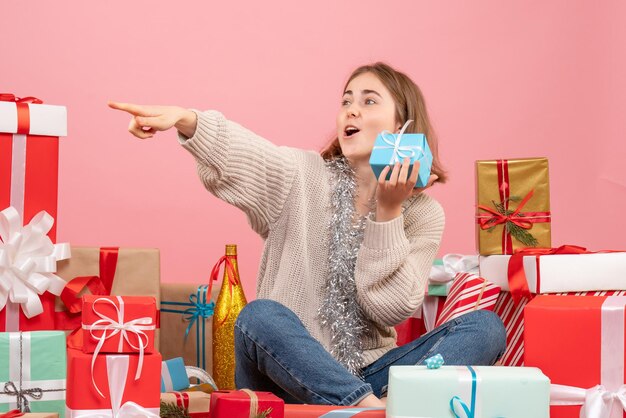 Vue de face jeune femme assise autour de différents cadeaux