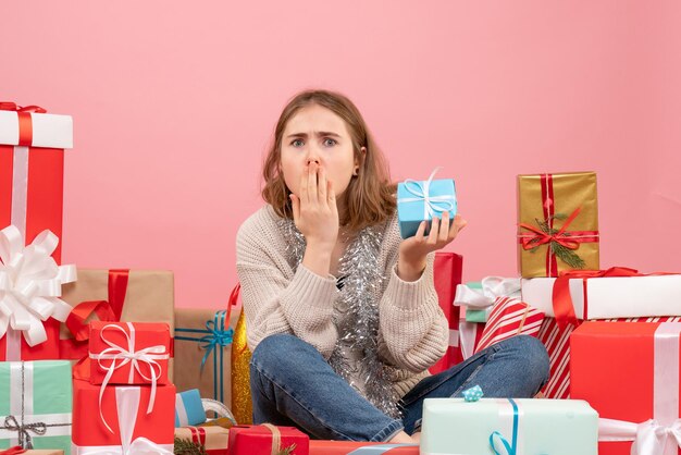 Vue de face jeune femme assise autour de différents cadeaux