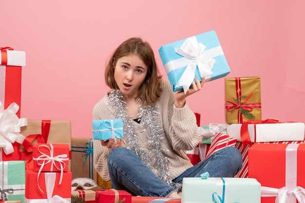 Vue de face jeune femme assise autour de différents cadeaux