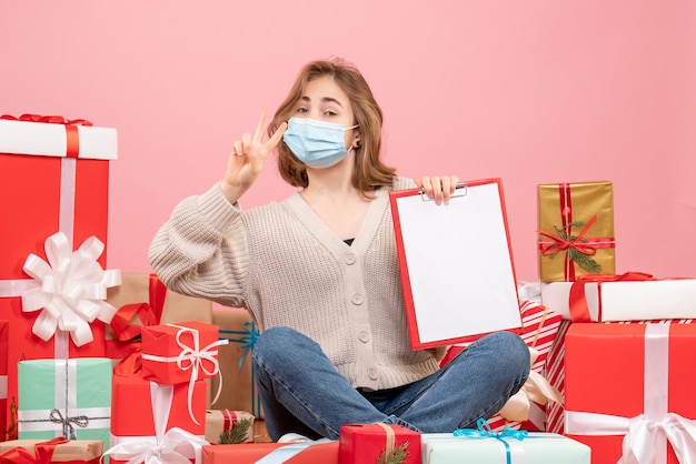 Vue de face jeune femme assise autour de Noël présente dans un masque stérile