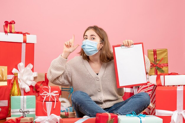 Vue de face jeune femme assise autour de Noël présente en masque avec note