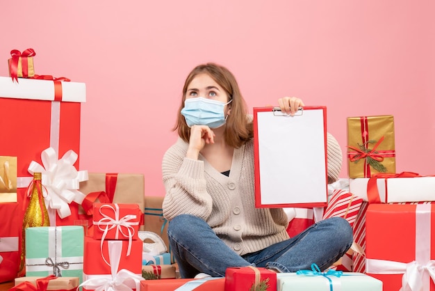 Vue de face jeune femme assise autour de Noël présente en masque avec note