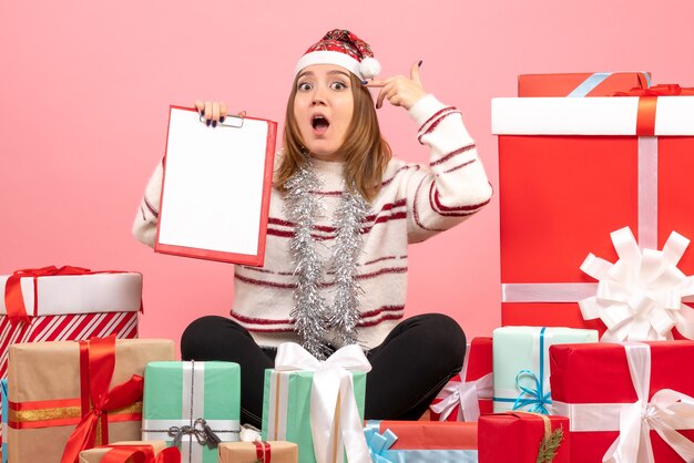 Vue de face jeune femme assise autour de Noël présente avec note de fichier