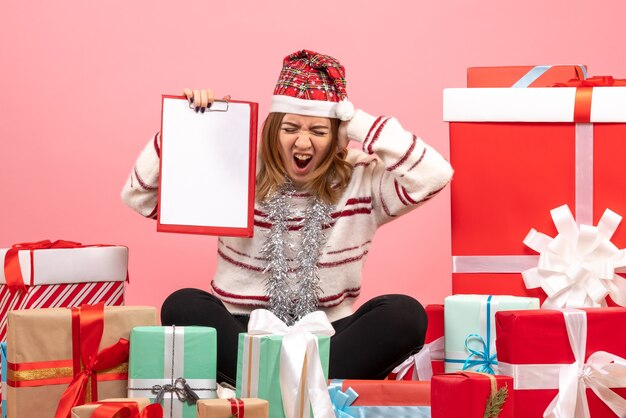 Vue de face jeune femme assise autour de Noël présente avec note de fichier