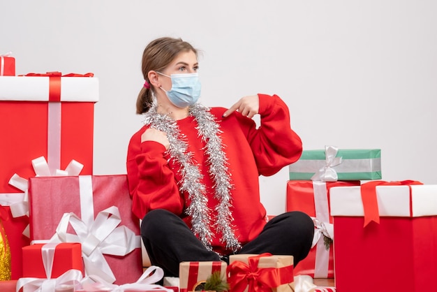 Vue de face jeune femme assise avec des cadeaux de Noël en masque