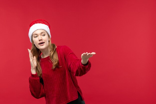 Vue de face jeune femme au bonnet rouge avec un visage surpris sur une femme rouge de vacances de bureau rouge