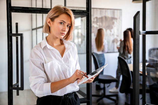 Vue de face jeune femme au bureau travaillant sur une tablette