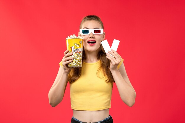 Vue de face jeune femme au cinéma holding pop-corn et billets en d lunettes de soleil sur le mur rouge cinéma cinéma couleur féminine