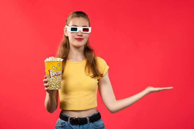 Vue de face jeune femme au cinéma holding pop-corn sur le mur rouge films théâtre cinéma snack femme film amusant