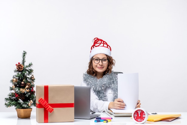 Vue de face jeune femme au lieu de travail travaillant avec des documents sur fond blanc