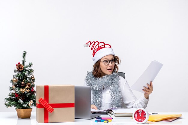 Vue de face jeune femme au lieu de travail travaillant avec des documents sur fond blanc