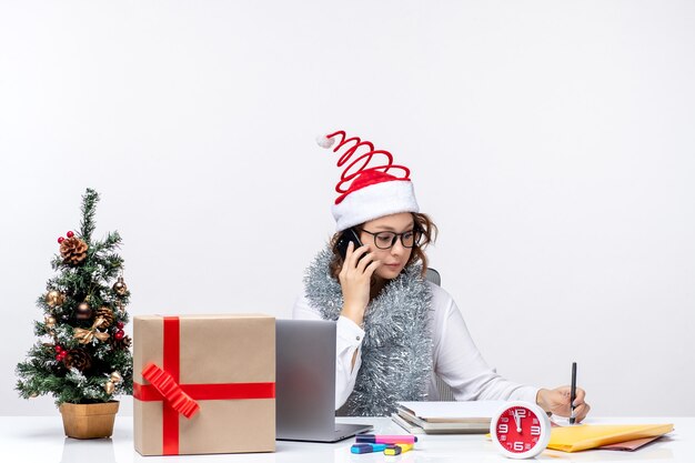 Vue de face jeune femme au travail pendant les jours de vacances à parler au téléphone sur fond blanc