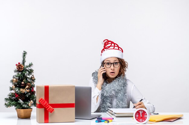 Vue de face jeune femme au travail pendant les jours de vacances à parler au téléphone sur fond blanc