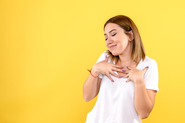 Vue de face de la jeune femme au visage ravi sur le mur jaune