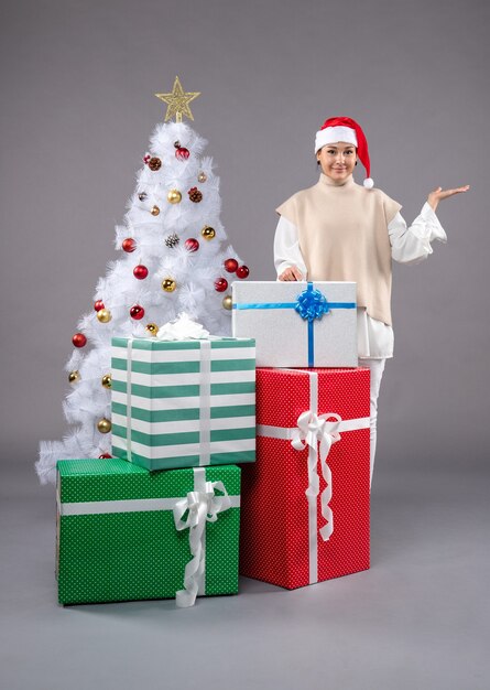 Vue de face jeune femme autour de cadeaux de vacances sur le gris