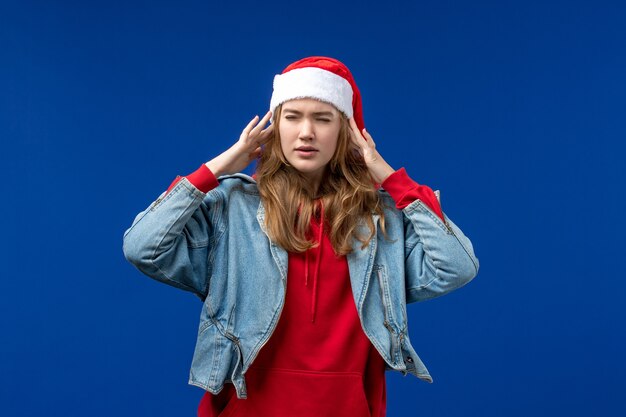 Vue de face jeune femme ayant des maux de tête sur fond bleu couleur de l'émotion de Noël