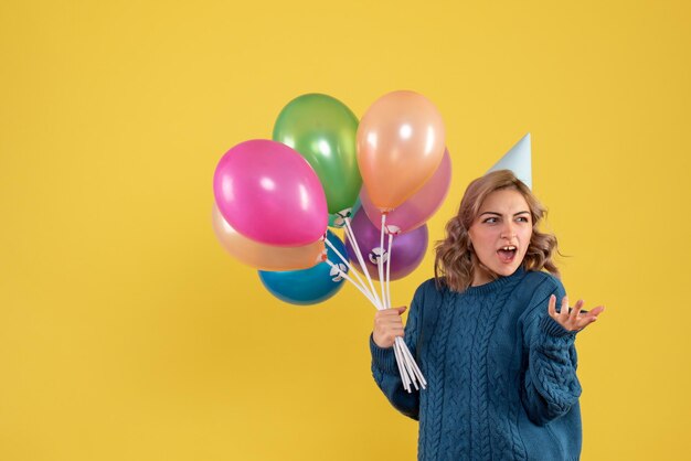 Vue de face jeune femme avec des ballons colorés