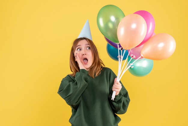 Vue de face jeune femme avec des ballons colorés