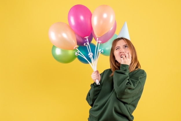 Vue de face jeune femme avec des ballons colorés