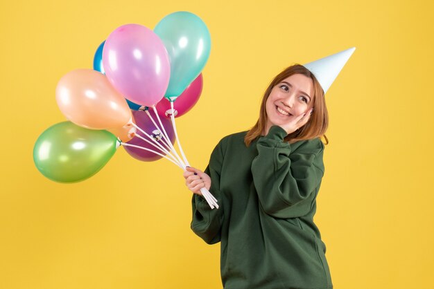 Vue de face jeune femme avec des ballons colorés