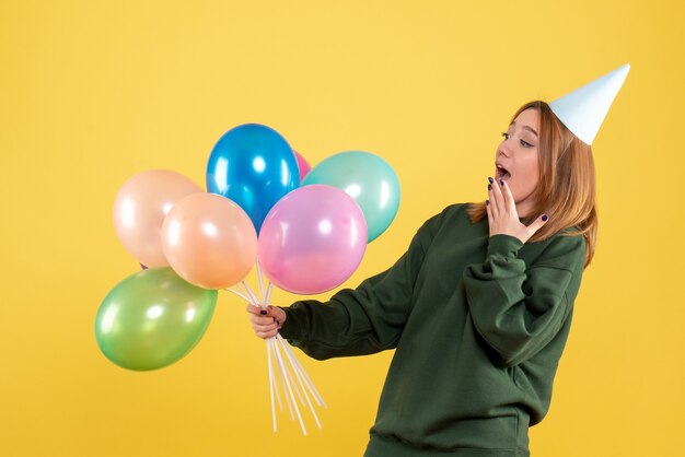 Vue de face jeune femme avec des ballons colorés