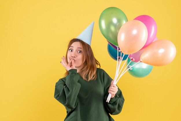 Vue de face jeune femme avec des ballons colorés