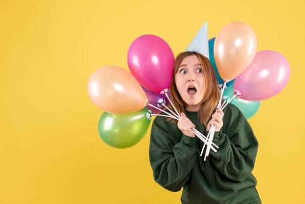 Vue de face jeune femme avec des ballons colorés