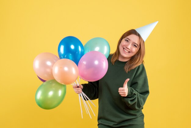 Vue de face jeune femme avec des ballons colorés