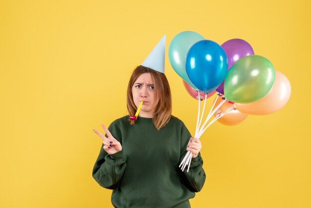 Vue de face jeune femme avec des ballons colorés