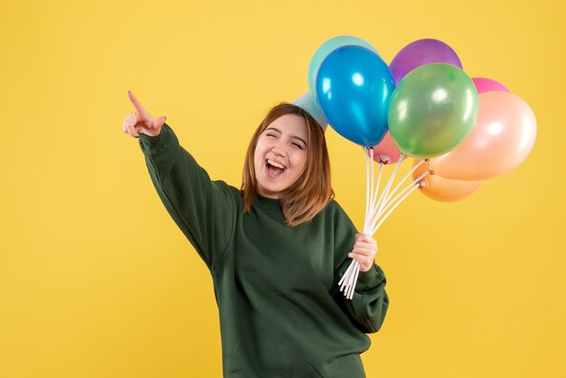 Vue de face jeune femme avec des ballons colorés