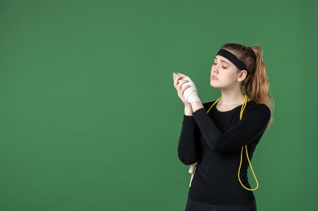 Vue de face jeune femme avec un bandage autour de son bras blessé sur fond vert athlète entraînement douleur santé blessure sport femme hôpital