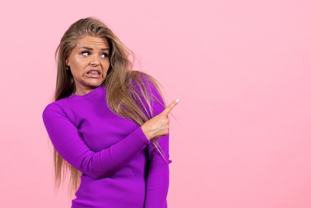 Photo gratuite vue de face d'une jeune femme en belle robe violette posant sur le mur rose