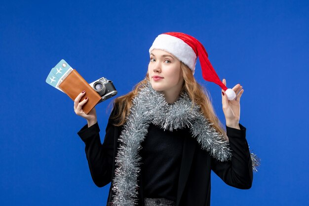 Vue de face d'une jeune femme avec des billets et un appareil photo sur le mur bleu