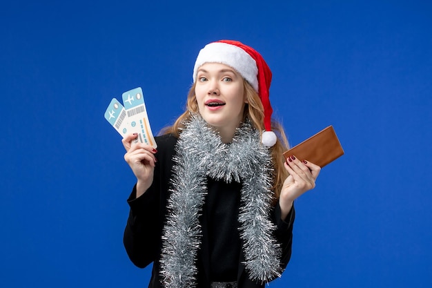 Vue de face d'une jeune femme avec des billets d'avion sur un mur bleu