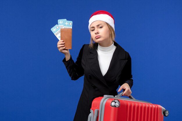 Vue de face jeune femme avec des billets et un sac sur les vacances de vacances avion mur bleu
