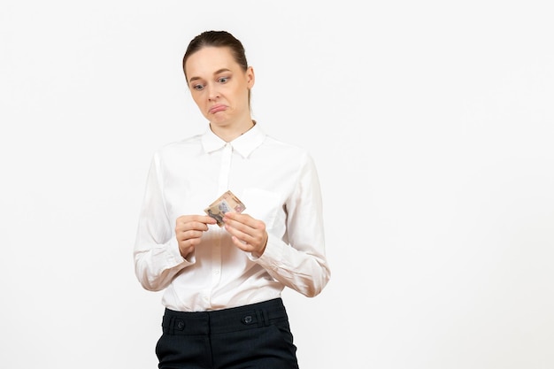 Vue de face jeune femme en blouse blanche tenant de l'argent sur fond blanc travail de bureau émotion féminine modèle de sentiment