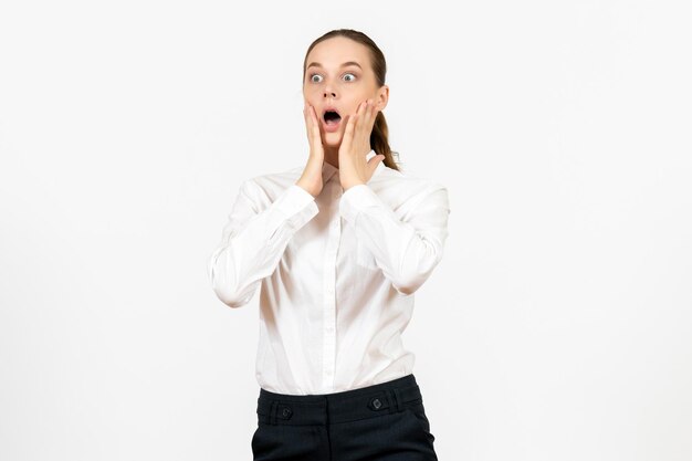 Vue de face jeune femme en blouse blanche avec visage choqué sur fond blanc travail de bureau émotions féminines modèle de sentiment