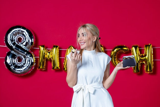 Photo gratuite vue de face jeune femme avec des bonbons au chocolat en mars décoré fond rouge business party égalité sensuelle féminine journée des femmes vacances