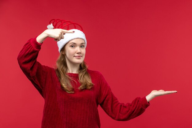 Vue de face jeune femme en bonnet de Noël rouge sur sol rouge vacances femme rouge