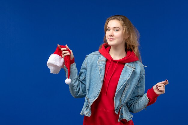 Vue de face jeune femme avec bonnet rouge sur fond bleu vacances couleur Noël nouvel an