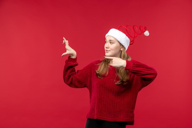 Vue de face jeune femme en bonnet rouge montrant la taille sur le sol rouge femme vacances rouge