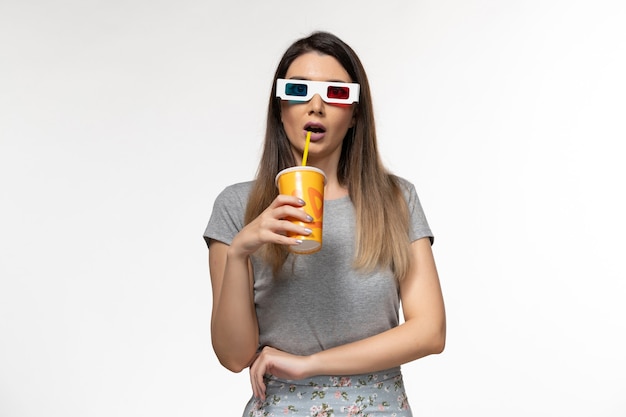 Vue de face jeune femme buvant du soda dans des lunettes de soleil sur une surface blanche