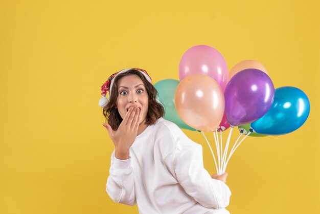 Vue de face jeune femme cachant des ballons colorés nouvel an Noël couleur vacances femme émotion