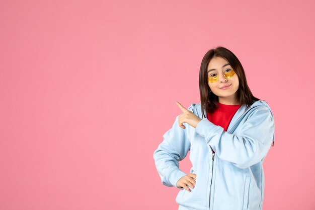 vue de face d'une jeune femme avec des cache-œil sur un mur rose