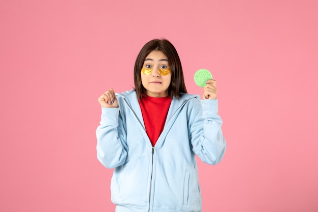 vue de face d'une jeune femme avec des cache-œil et une petite éponge sur un mur rose