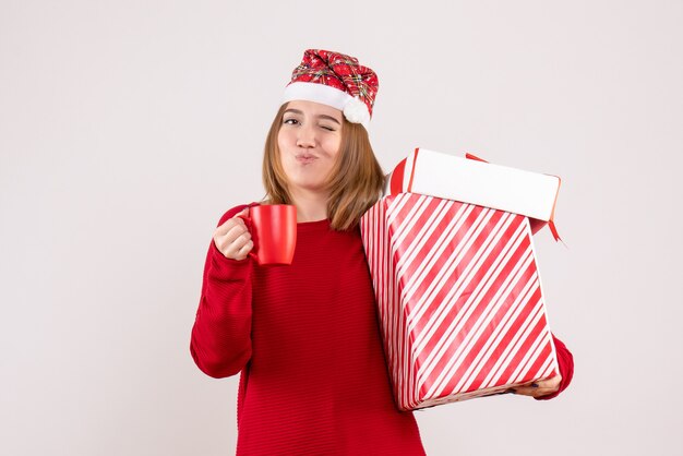 Vue de face jeune femme avec cadeau et tasse de thé