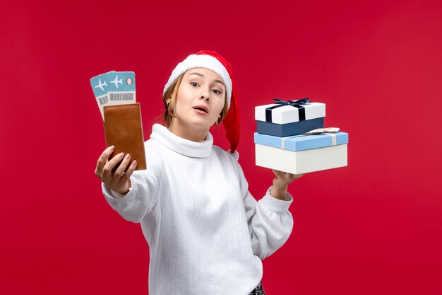 Vue de face jeune femme avec des cadeaux et des billets sur un bureau rouge