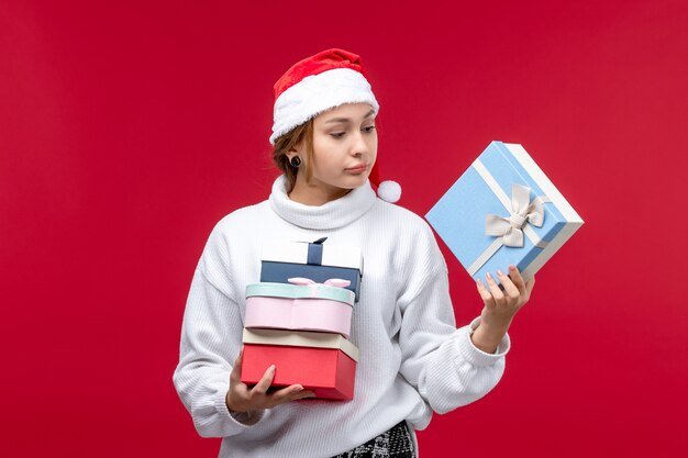 Vue de face jeune femme avec des cadeaux de vacances sur un bureau rouge