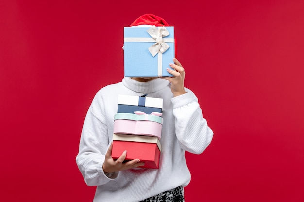 Photo gratuite vue de face jeune femme avec des cadeaux de vacances sur fond rouge